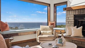 Un rincón acogedor con vistas al océano, que incluye una chimenea y una mesa redonda con adornos.