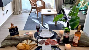 A cozy dining setup with a table set for two, featuring a candle, wine glasses, a bottle of wine, and a plate of food.
