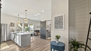 A modern kitchen with a central island, a dining area with a sofa, and a living space with a sofa and a coffee table. - NEW!!! Modern cottage and perfect location! (Bluffton)