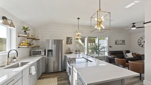 A modern kitchen with a central island, stainless steel appliances, and pendant lighting. - NEW!!! Modern cottage and perfect location! (Bluffton)