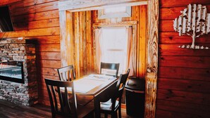 Un interior de madera con una mesa y sillas de comedor, una chimenea de piedra y un diseño rústico de pared.