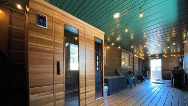 Una cabana de fusta amb un porxo, seients integrats i llums penjants.
