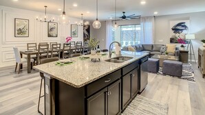 Una cucina moderna con un'isola grande, mobili scuri e illuminazione a sospensione.