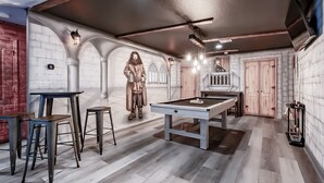 Una sala biliardo con tavolo da biliardo, sgabelli e una statua.