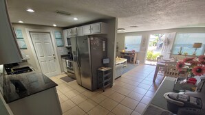 A kitchen with a refrigerator, oven, and microwave. There is a dining area with a table and chairs.