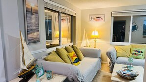 Um quarto aconchegante com uma cama, uma mesinha de cabeceira com abajur e uma janela com vista para o mar.