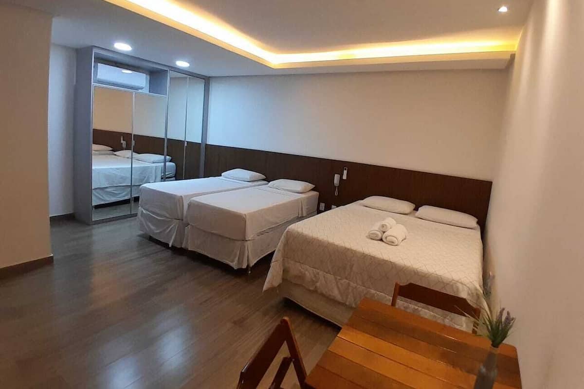 A hotel room with two beds, a wooden table, and a mirror.