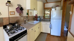 Una cocina compacta con estufa a gas, lavamanos y refrigerador blanco.