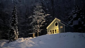 Un paisaje cubierto de nieve con una casa iluminada por una luz cálida.