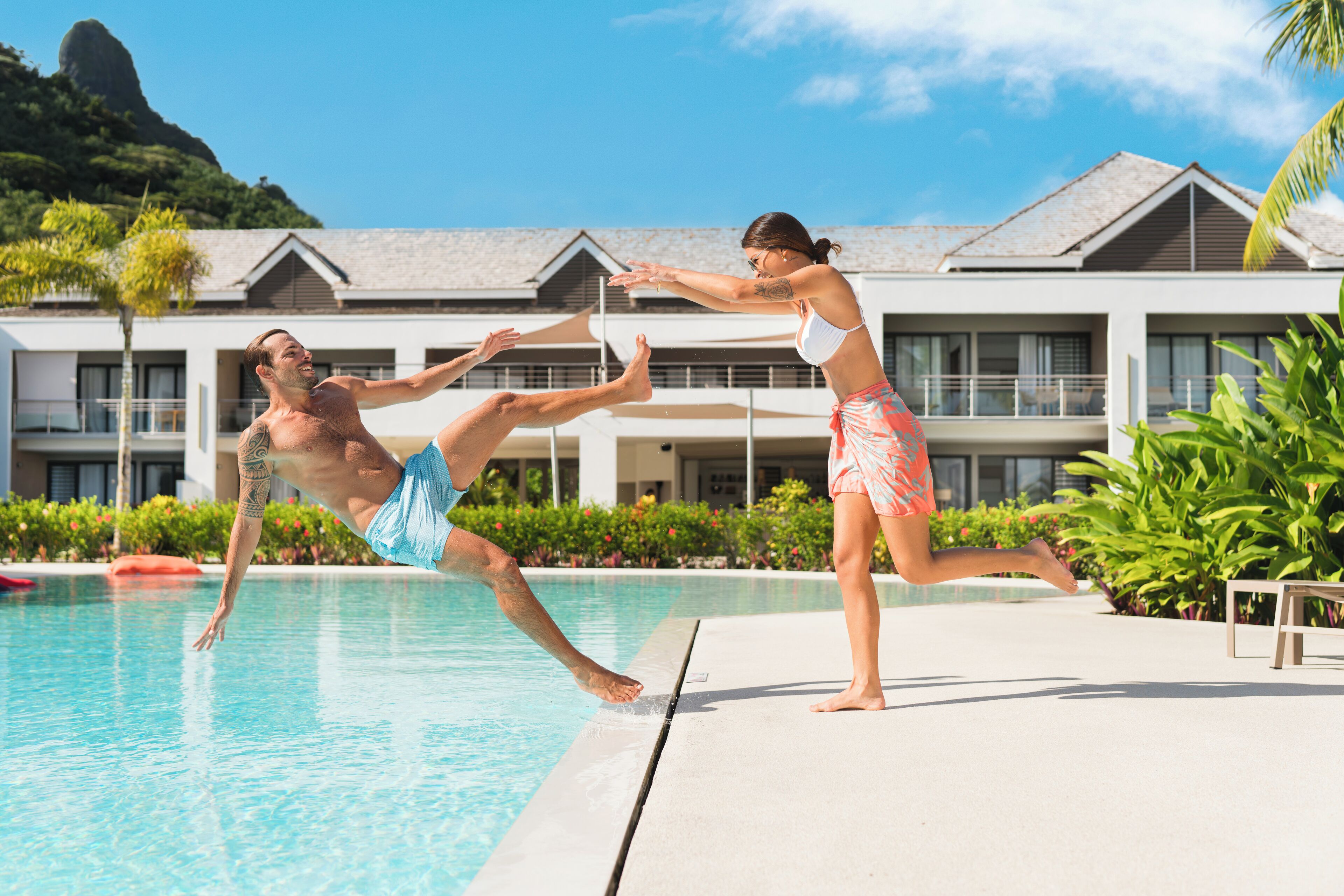A swimming pool with a person diving into the water and another standing on the edge.