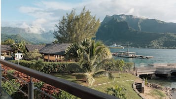 A coastal view with a wooden house, palm trees, and a dock extending into the water.