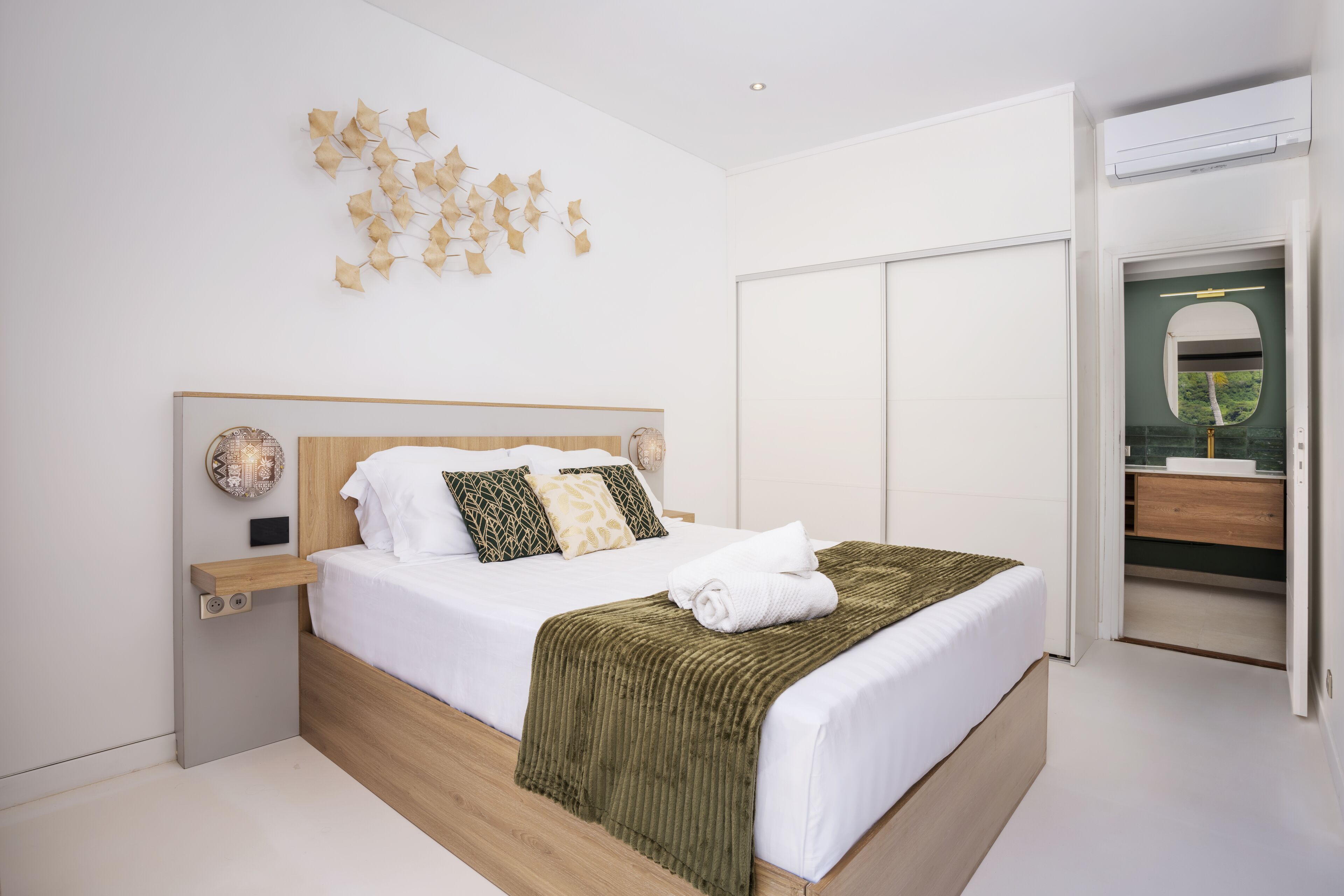 Un dormitorio moderno con cama de madera, ropa de cama blanca, un plaid verde y una obra de arte original en la pared.