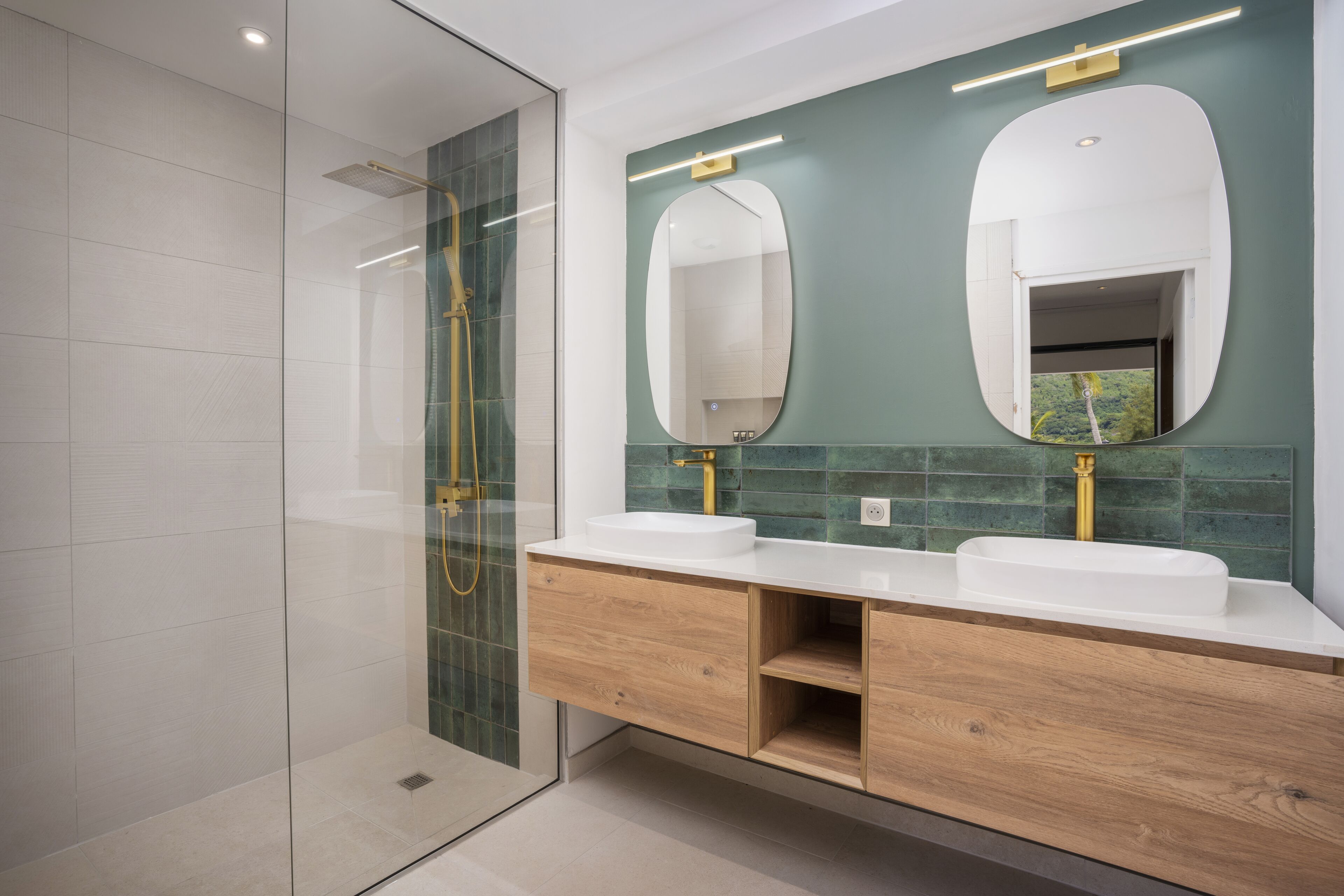 Un baño moderno con dos lavamanos, un espejo grande y una cabina de ducha con paredes de vidrio.