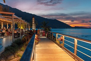 A wooden deck with a railing overlooking a body of water, with a mountain in the background.