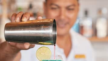 Un barman verse une boisson dans un verre, en y ajoutant une tranche de citron vert.