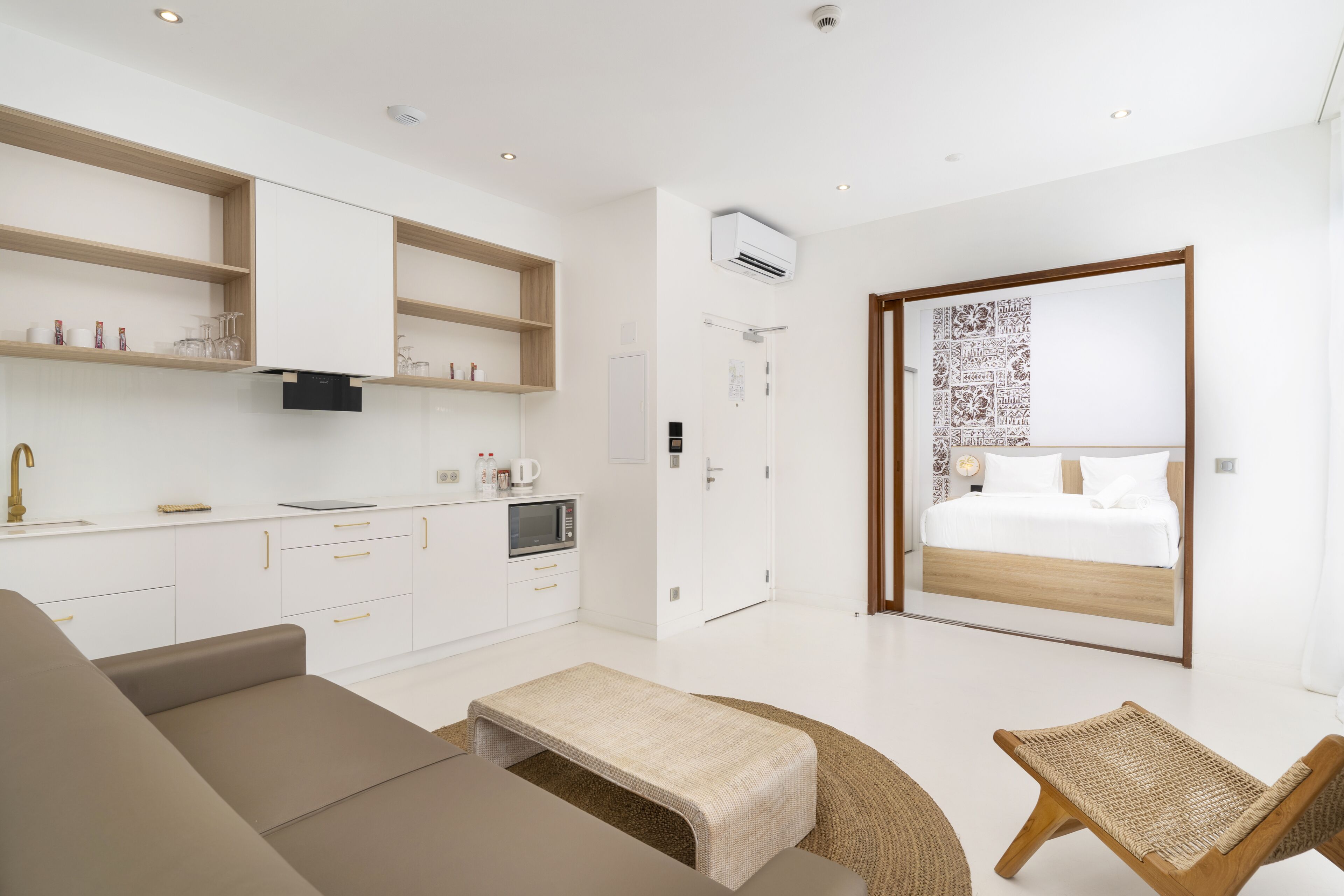 Una habitación moderna y luminosa, con kitchenette, cama y zona de estar.