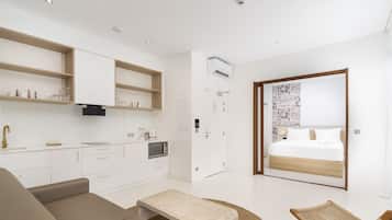 Una habitación moderna y luminosa, con kitchenette, cama y zona de estar.