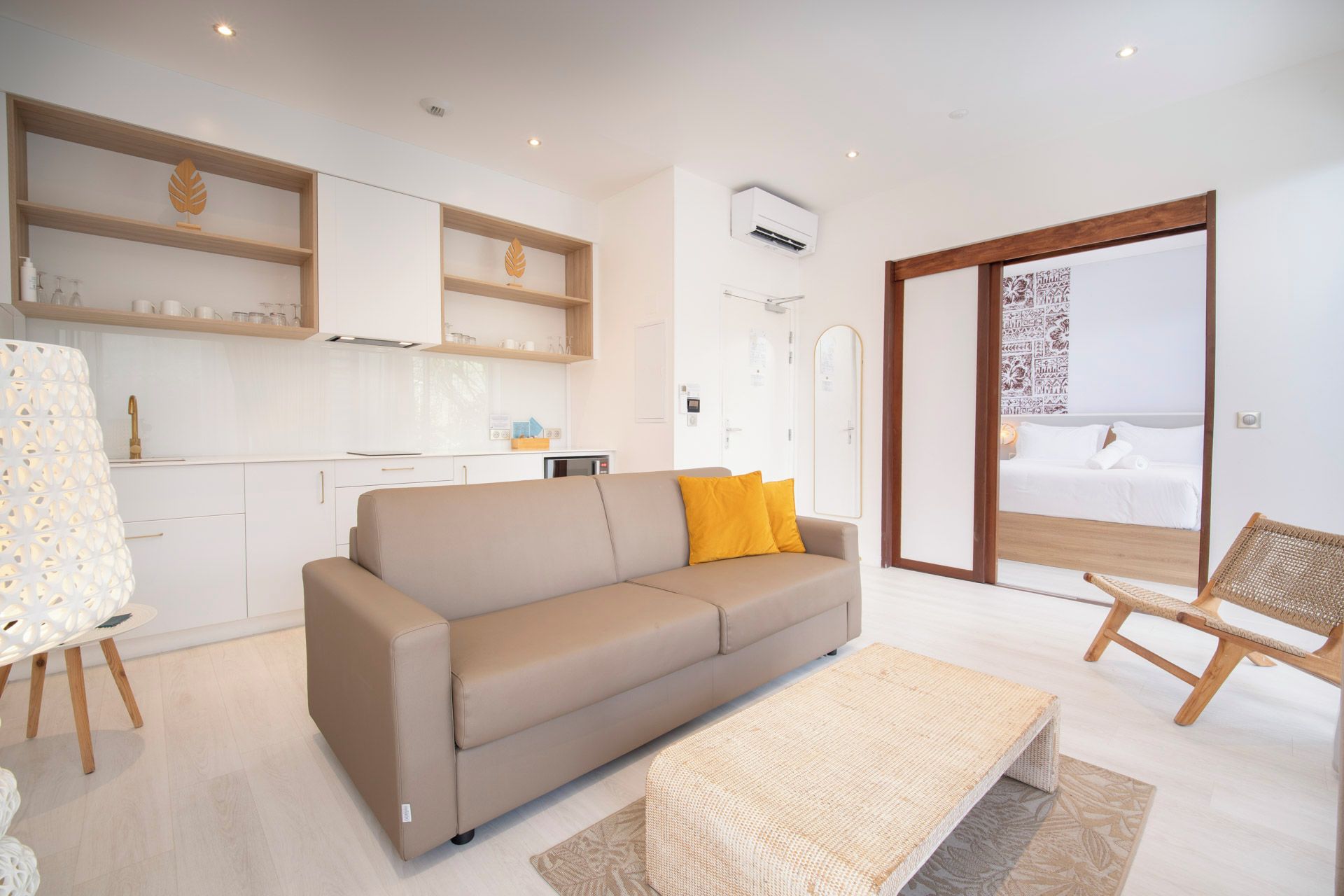 A modern living room with a sofa, a coffee table, and a view of a balcony.