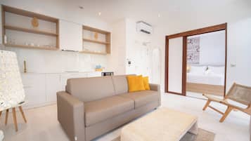 A modern living room with a sofa, a coffee table, and a view of a balcony.