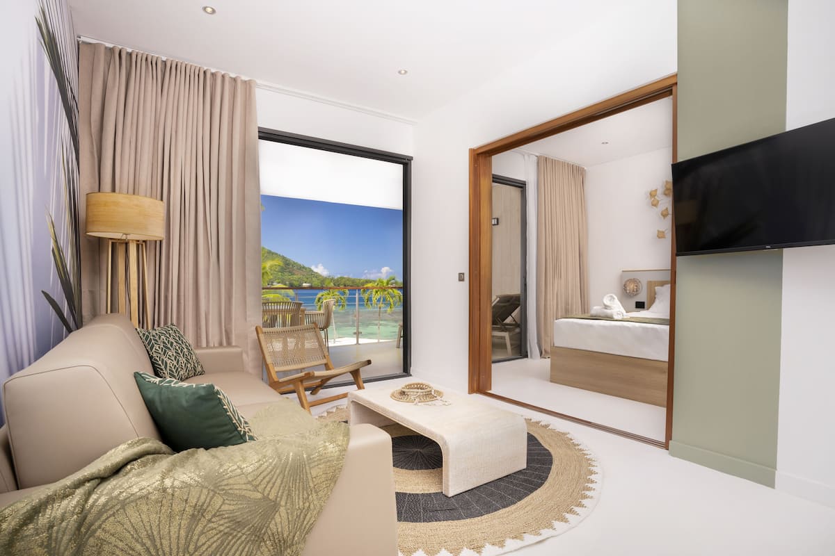 Ett modernt hotellrum med ett stort fönster, en soffa, ett soffbord och en säng.