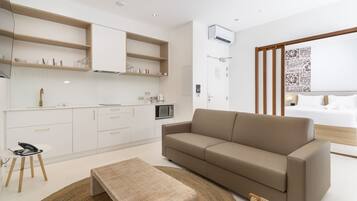 A modern, well-lit room with a kitchenette, a sofa, a bed, and a patterned wall.