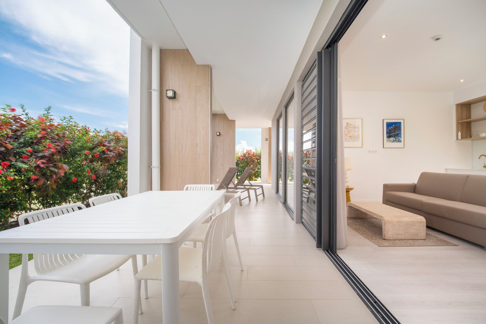 A modern living space with a dining area, a sofa, and a view of the outdoors.