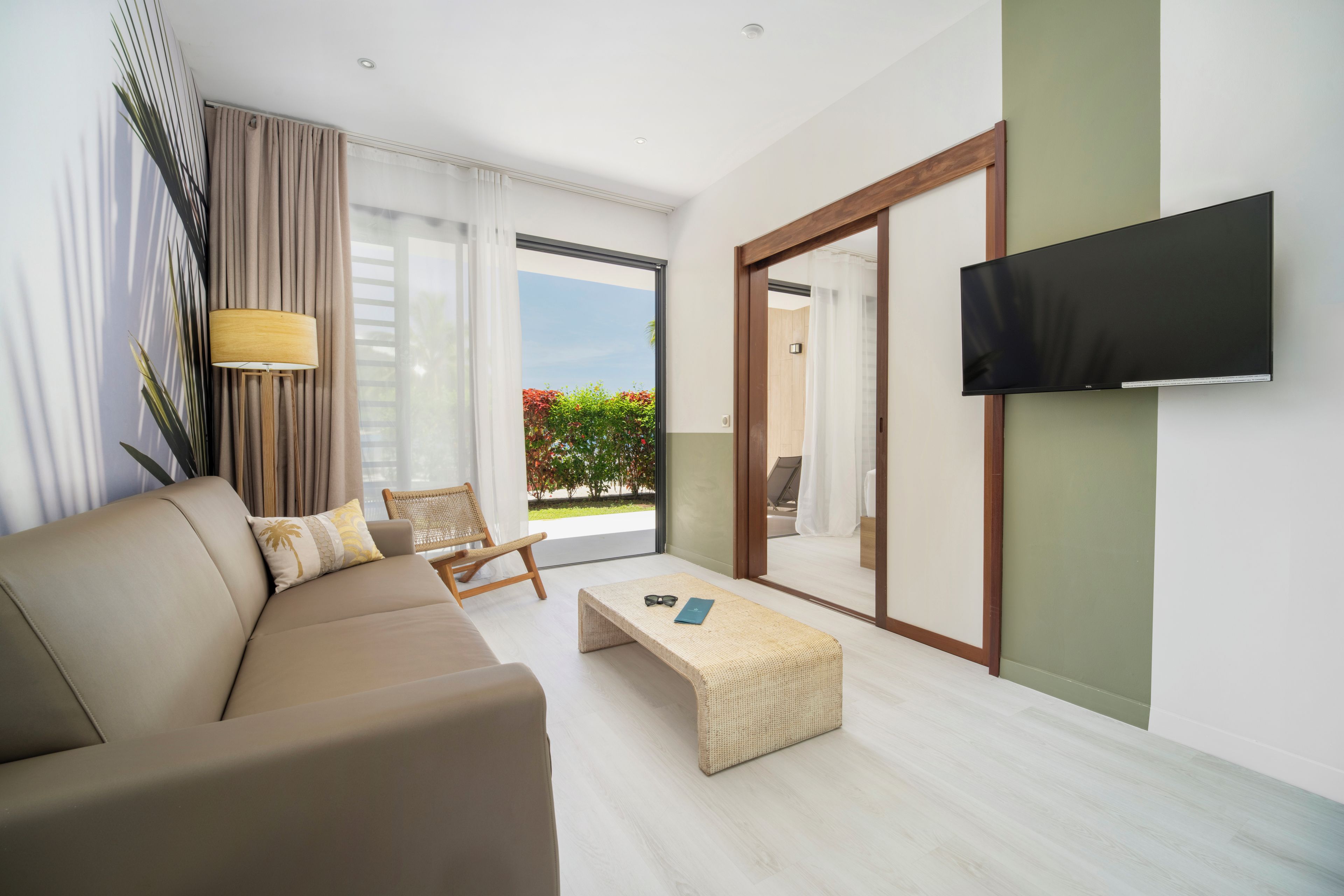 A modern living room with a sofa, a chair, a coffee table, and a television mounted on the wall.