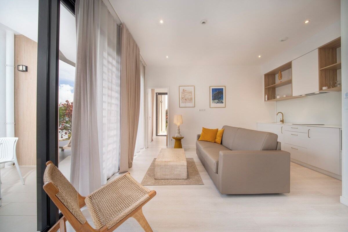 Suite familiar, 2 habitaciones, vista parcial al océano, planta baja | Área de sala de estar | Televisión de pantalla plana de 40 pulgadas con canales vía satélite