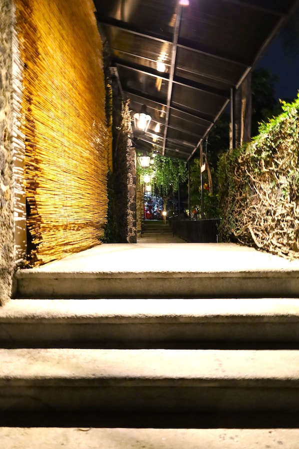 A staircase leading to a covered area with a metal roof, surrounded by greenery and stone walls. - Hotel Grand Vista Cuernavaca (Cuernavaca)