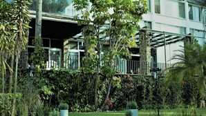 A modern building with a covered outdoor area, surrounded by lush greenery and a well-maintained garden. - Hotel Grand Vista Cuernavaca (Cuernavaca)