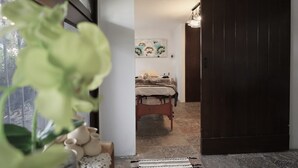 Een slaapkamer met een bed, een schilderij aan de muur en een deur naar een andere kamer.