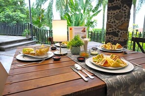 A wooden table set outdoors with plates of food, a lamp, and a menu. - Hotel Grand Vista Cuernavaca (Cuernavaca)