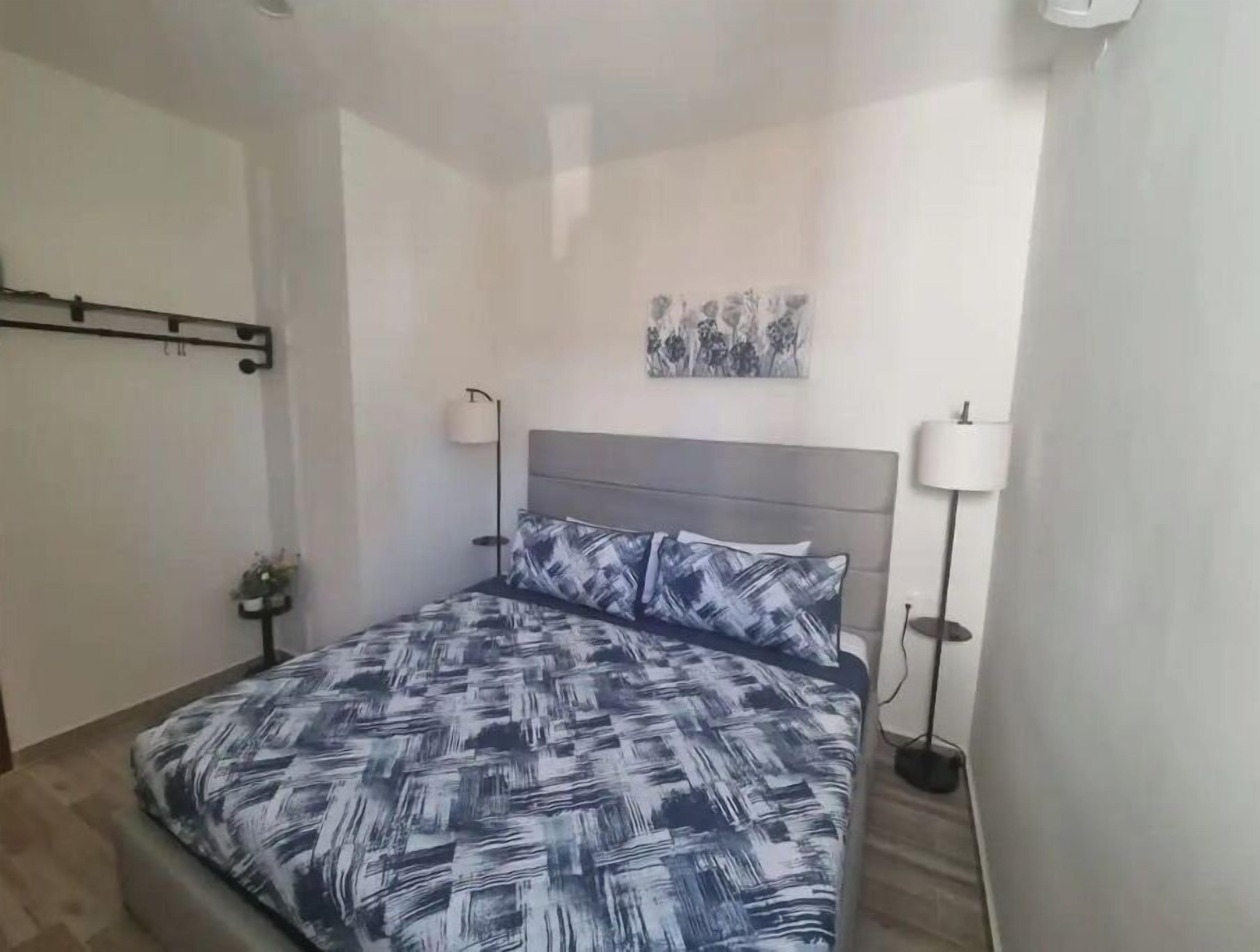 Une chambre à coucher comprenant un lit, deux lampes de chevet, une œuvre d’art accrochée au mur et un luminaire fixé au plafond.