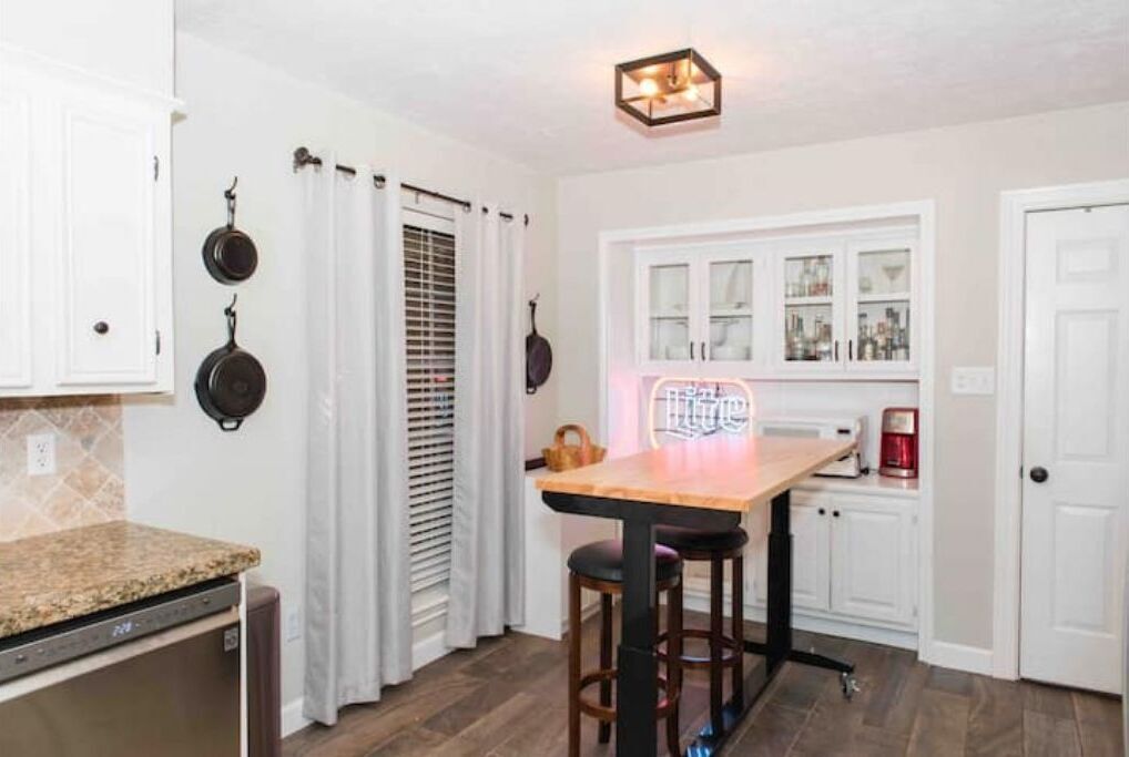 A kitchen with a wooden countertop, a dining table with stools, and a built-in oven.