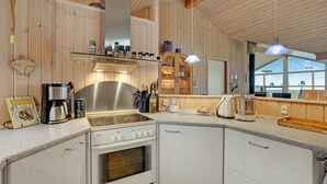 A modern kitchen with a Bosch stove, wooden cabinetry, and a large window offering a view of the outdoors. - Beautiful home in Thyholm with WiFi (Thyholm)