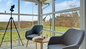 A conservatory with large windows, a tripod, a table with drinks, and two chairs. - Beautiful home in Thyholm with WiFi (Thyholm)