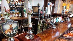 Eine Barbereitschaft mit mehreren Zapfhähnen, darunter Marken wie Guinness und Heineken, und ein dekoratives Glas mit einem Hirsch-Design.