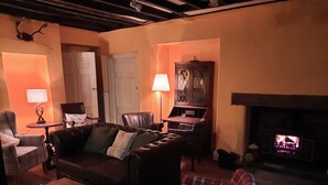 Ein gemütliches Wohnzimmer mit Kamin, Ledermöbeln und einem Karo-Sessel.