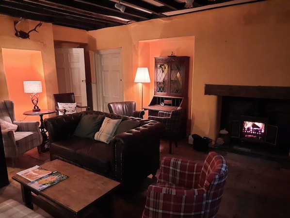 Una sala de estar acogedora con chimenea, muebles de cuero y un sillón a cuadros.