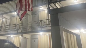 A building with a flagpole, a car parked in front, and a balcony with railings. - Falls of Rough Motel (Falls of Rough)