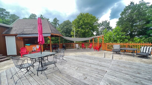 A wooden deck with outdoor furniture, a barbecue area, and a covered seating area under a canopy. - Falls of Rough Motel (Falls of Rough)