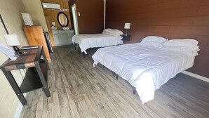 A hotel room with two beds, a wooden desk, a mirror, and a dresser. - Falls of Rough Motel (Falls of Rough)