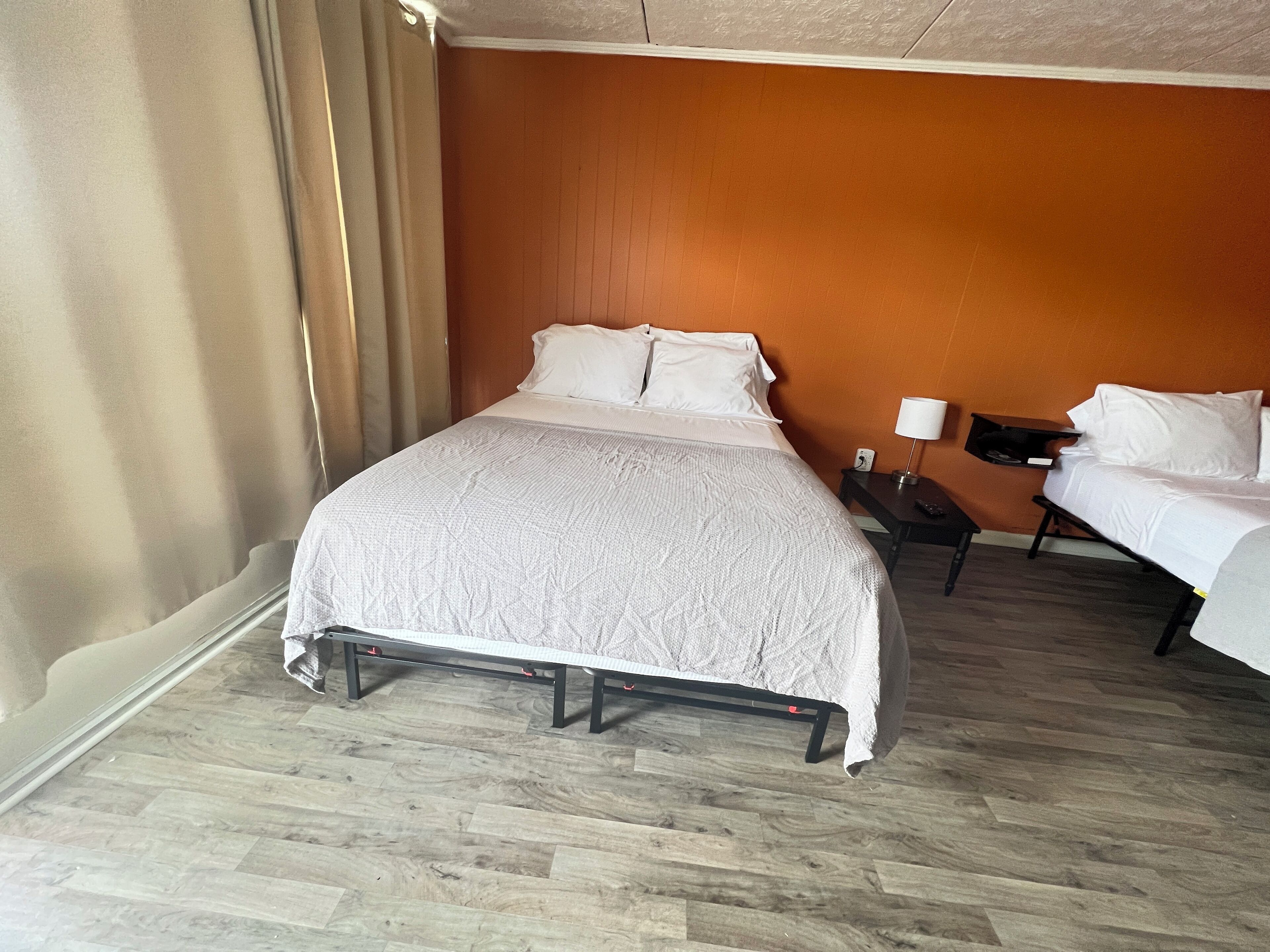 A hotel room with a large bed, a bedside table with a lamp, and a wooden floor.
