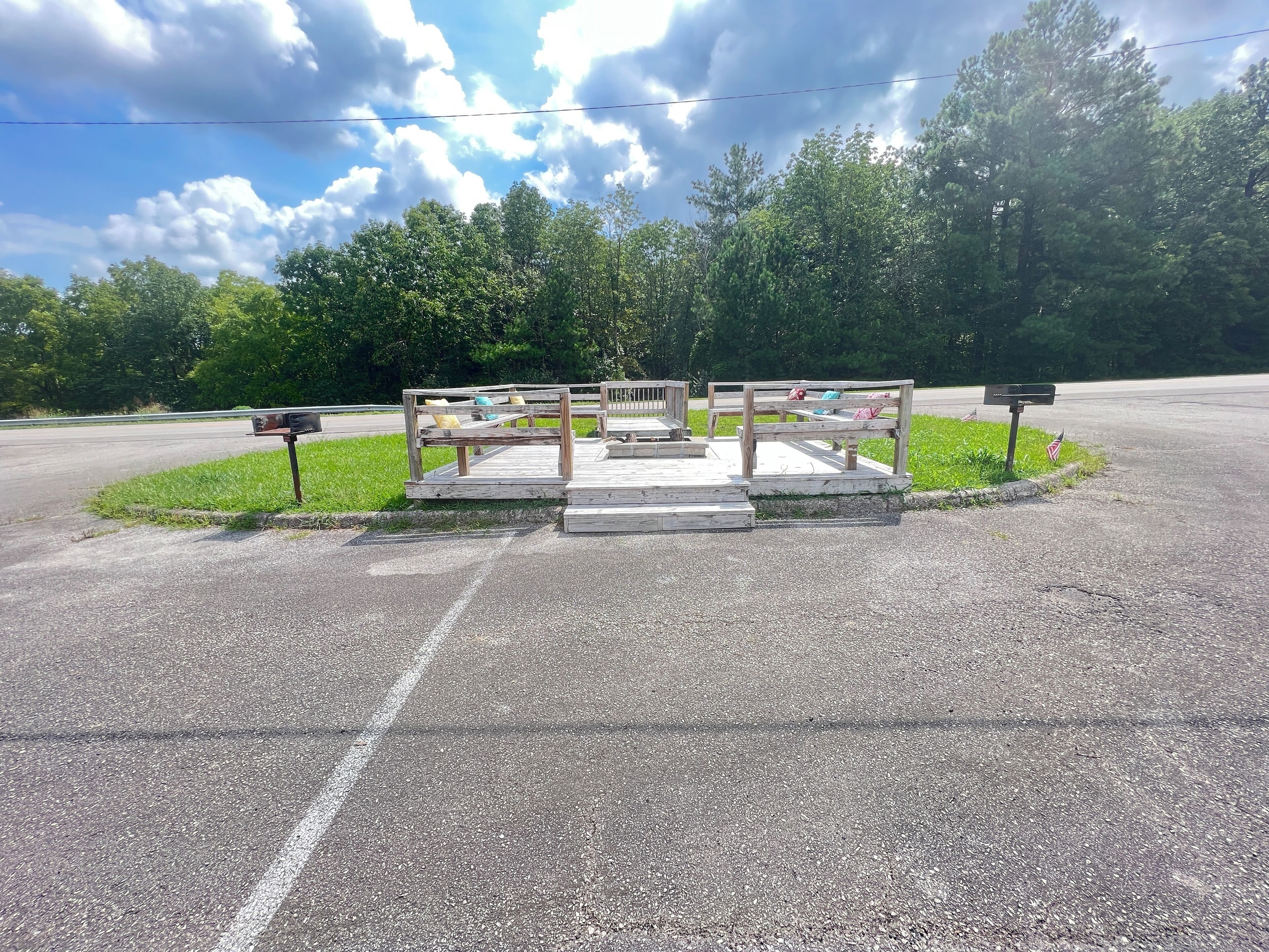 A wooden bench with a mailbox and a sign in a park setting.