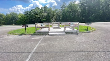 A wooden bench with a mailbox and a sign in a park setting.