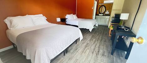 A hotel room with two beds, a desk, a mirror, and a television.