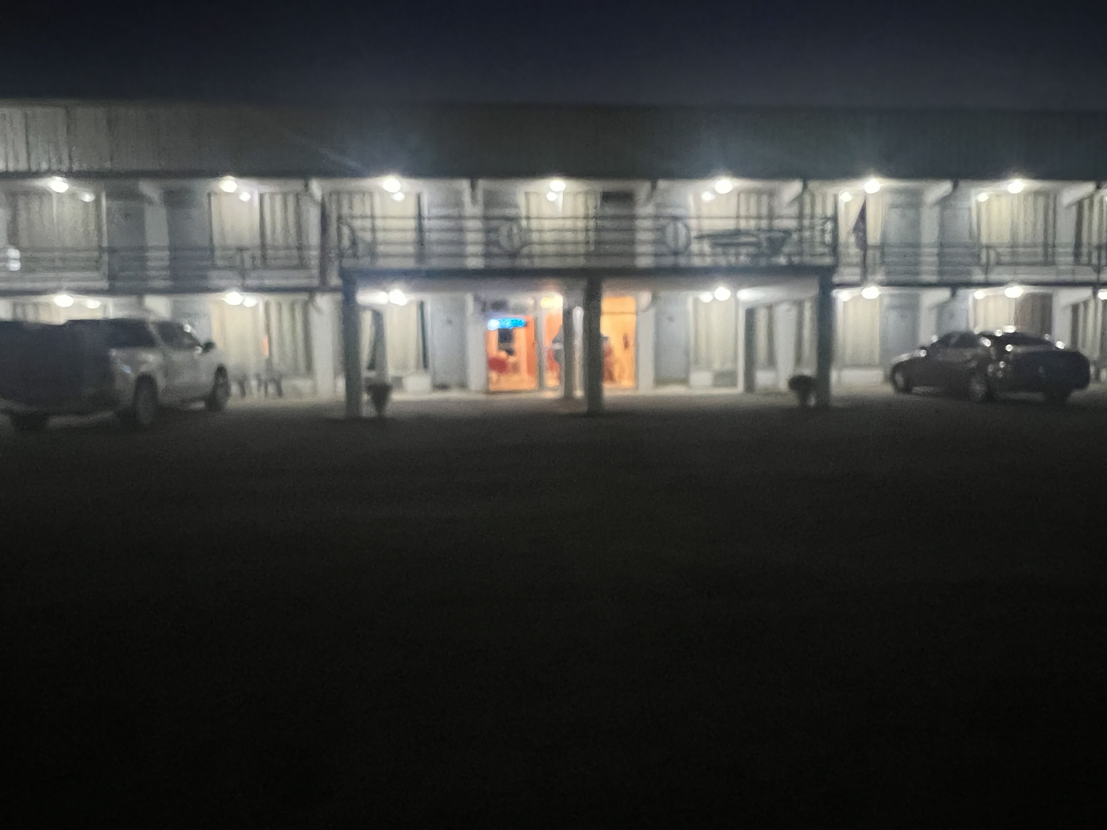 A building with multiple floors, a central entrance, and several cars parked in front.