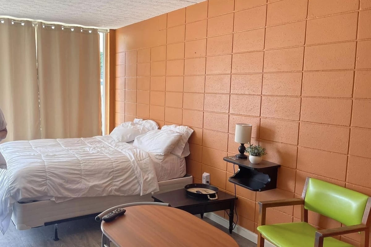 A hotel room with a bed, a small table, a chair, and a nightstand.