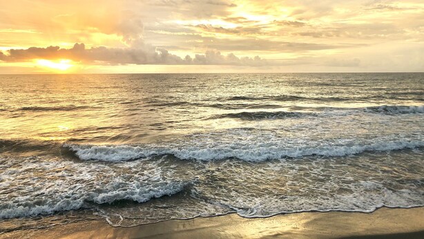 A beach with waves and a sunset. - Relaxing Tropical Getaway! Coral Cottage Melbourne- family and pet friendly home (Melbourne)