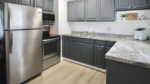 A modern kitchen with dark cabinets, stainless steel appliances, and a granite countertop. - Relaxing Tropical Getaway! Coral Cottage Melbourne- family and pet friendly home (Melbourne)